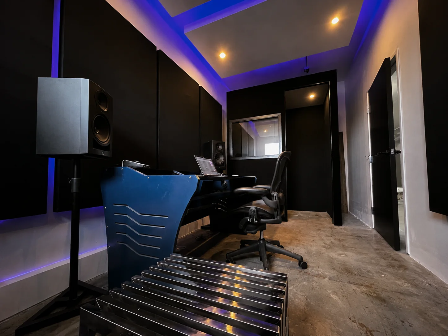 Wide Studio B control-room view with workstation and vocal-booth window